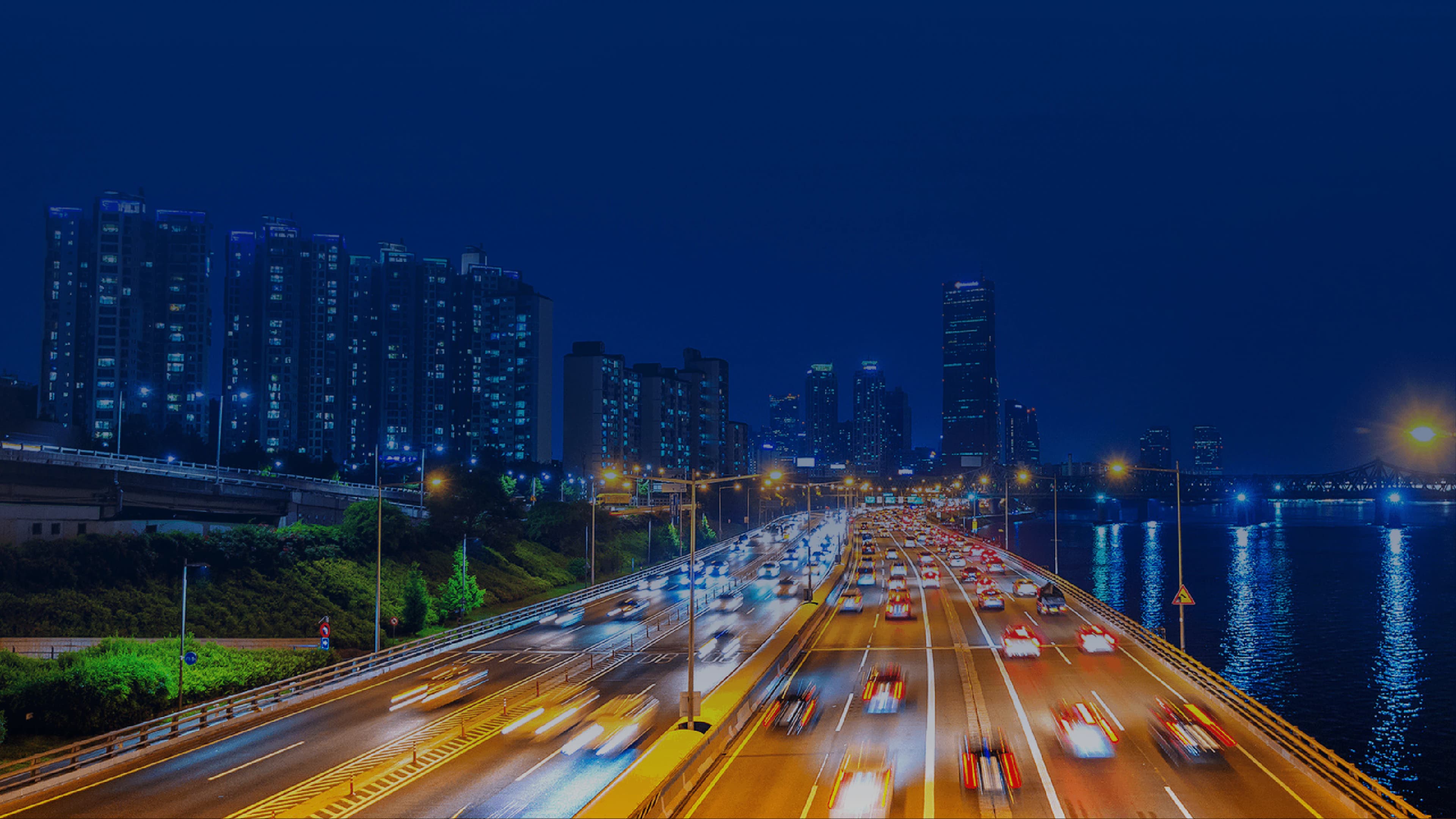 Night highway cityscape with light trails and urban skyline